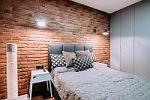 Aranżacja sypialni w stylu industrialnym z ceglaną ścianą i surowym oświetleniem